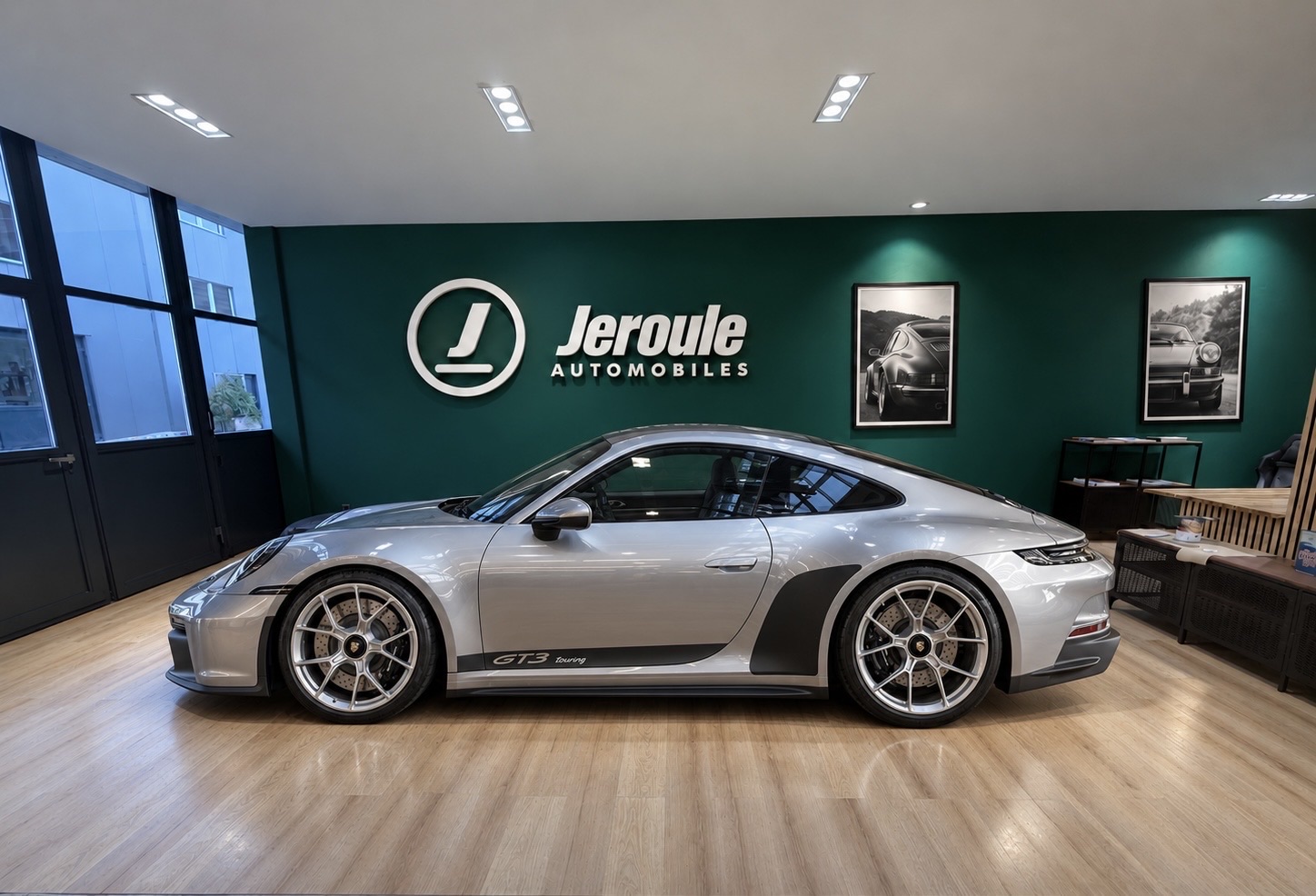 Showroom Jeroule automobiles à Cressier (FR) — Porsche 911 GT3 exposée devant le mur émeraude signature avec le logo J